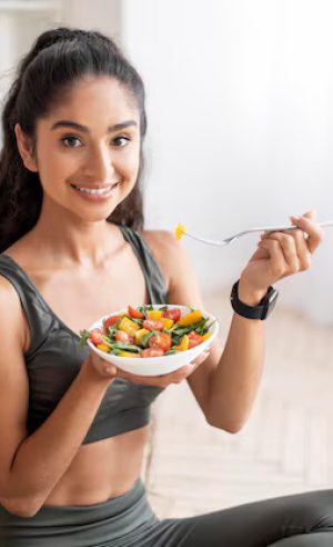 sporty-young-indian-woman-eating-fresh-salad-after-workout_116547-78097